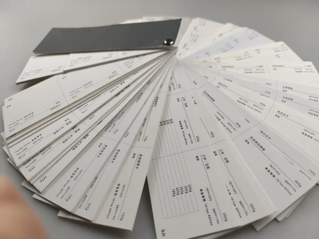 Paper swatch fan · dark cover; photographed paper sample book with original labels